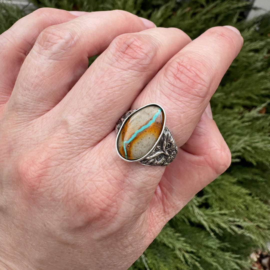 Close-up of Royston ribbon turquoise showing distinctive blue vein in handcrafted sterling silver owl ring. Made in Fort Collins, Colorado.
