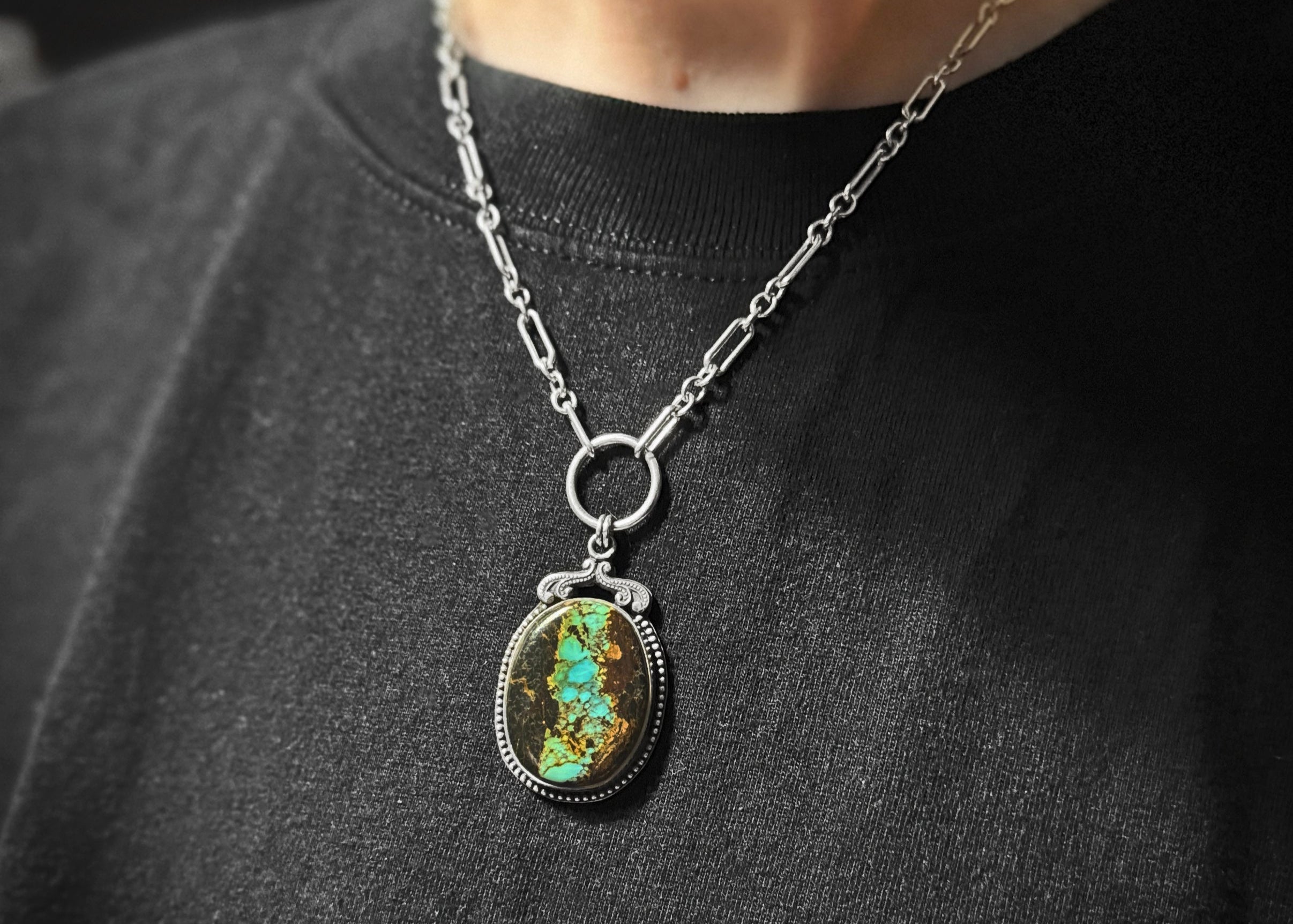 Handcrafted Blackjack Turquoise statement pendant necklace featuring genuine Nevada turquoise stone with vibrant blue-green turquoise in dramatic black matrix, set in sterling silver beaded bezel with art nouveau inspired crown detail, hanging from a silver paperclip chain with O-ring connector