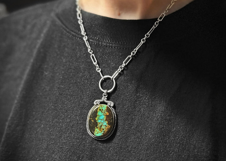 Handcrafted Blackjack Turquoise statement pendant necklace featuring genuine Nevada turquoise stone with vibrant blue-green turquoise in dramatic black matrix, set in sterling silver beaded bezel with art nouveau inspired crown detail, hanging from a silver paperclip chain with O-ring connector