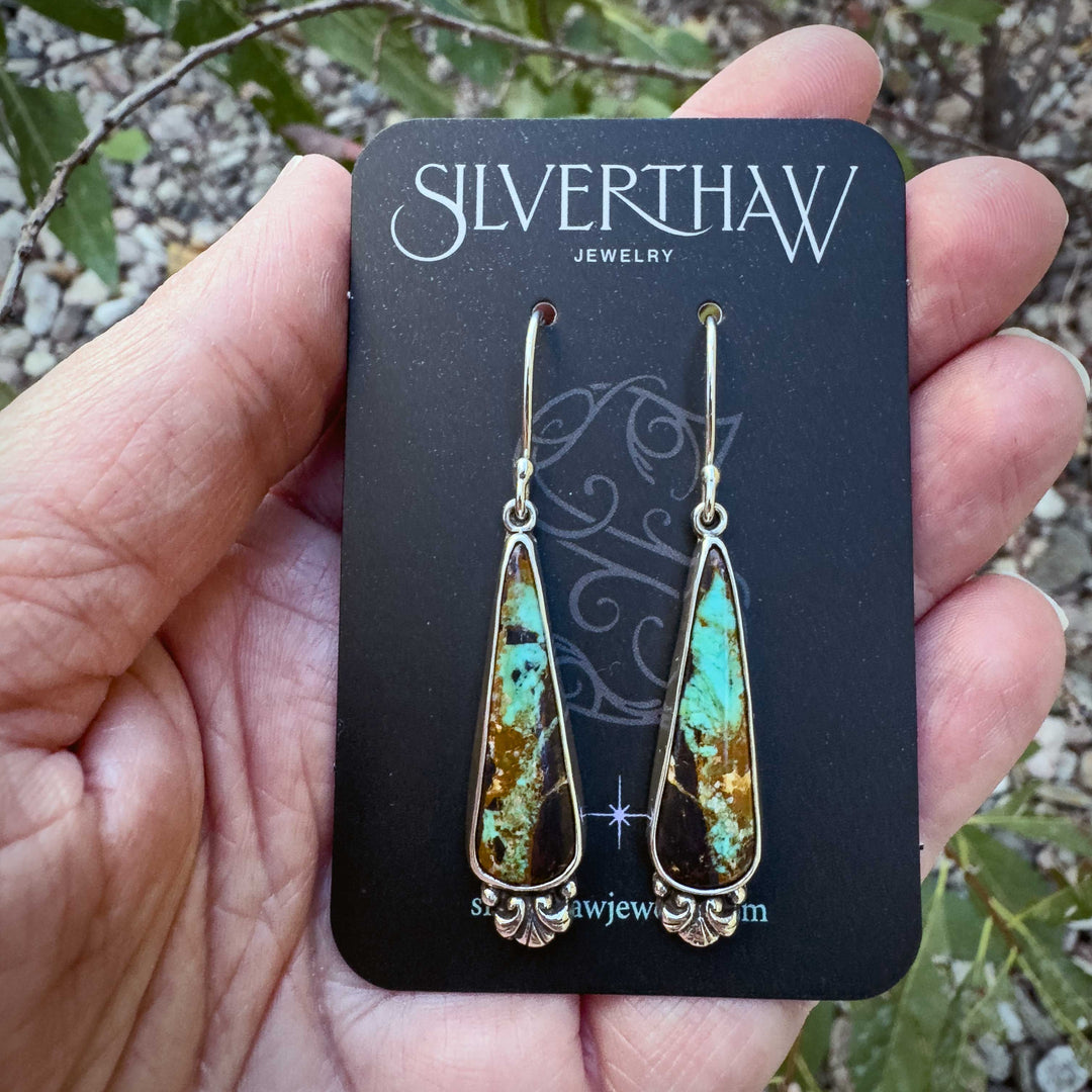 Black Jack turquoise earrings displayed on Silverthaw Jewelry card, handmade sterling silver teardrop design with earthy turquoise and dark matrix pattern.