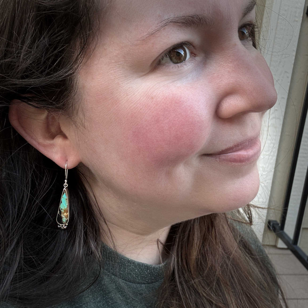 Model wearing Black Jack turquoise drop earrings in sterling silver, showing elegant teardrop shape and comfortable everyday length.