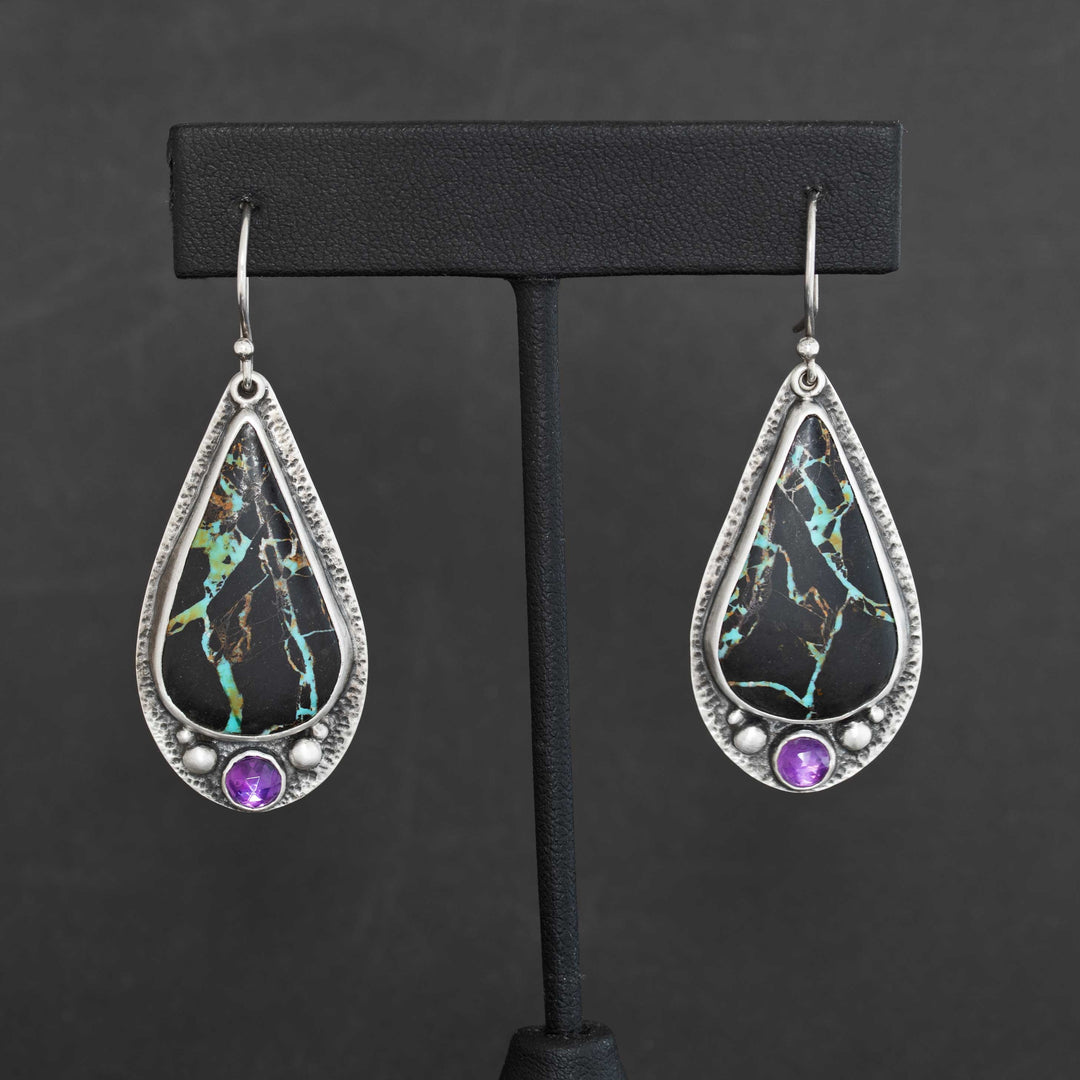 Blackjack turquoise and amethyst drop earrings in handmade sterling silver displayed on black jewelry stand