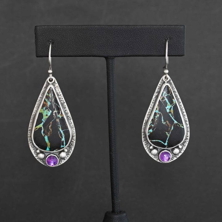Blackjack turquoise and amethyst drop earrings in handmade sterling silver displayed on black jewelry stand