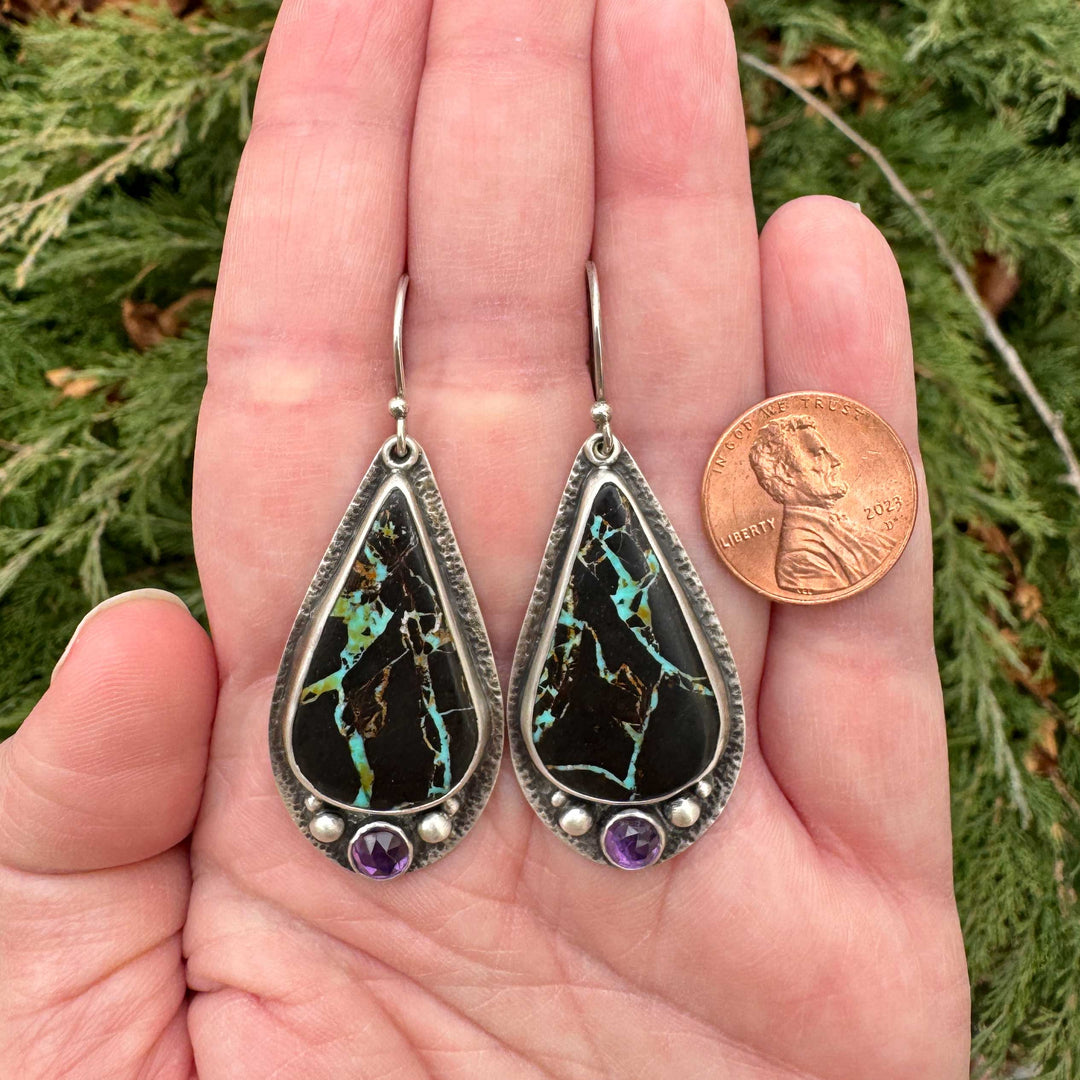 Blackjack turquoise and amethyst sterling silver drop earrings held in hand next to penny for size reference