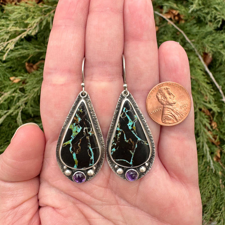 Blackjack turquoise and amethyst sterling silver drop earrings held in hand next to penny for size reference