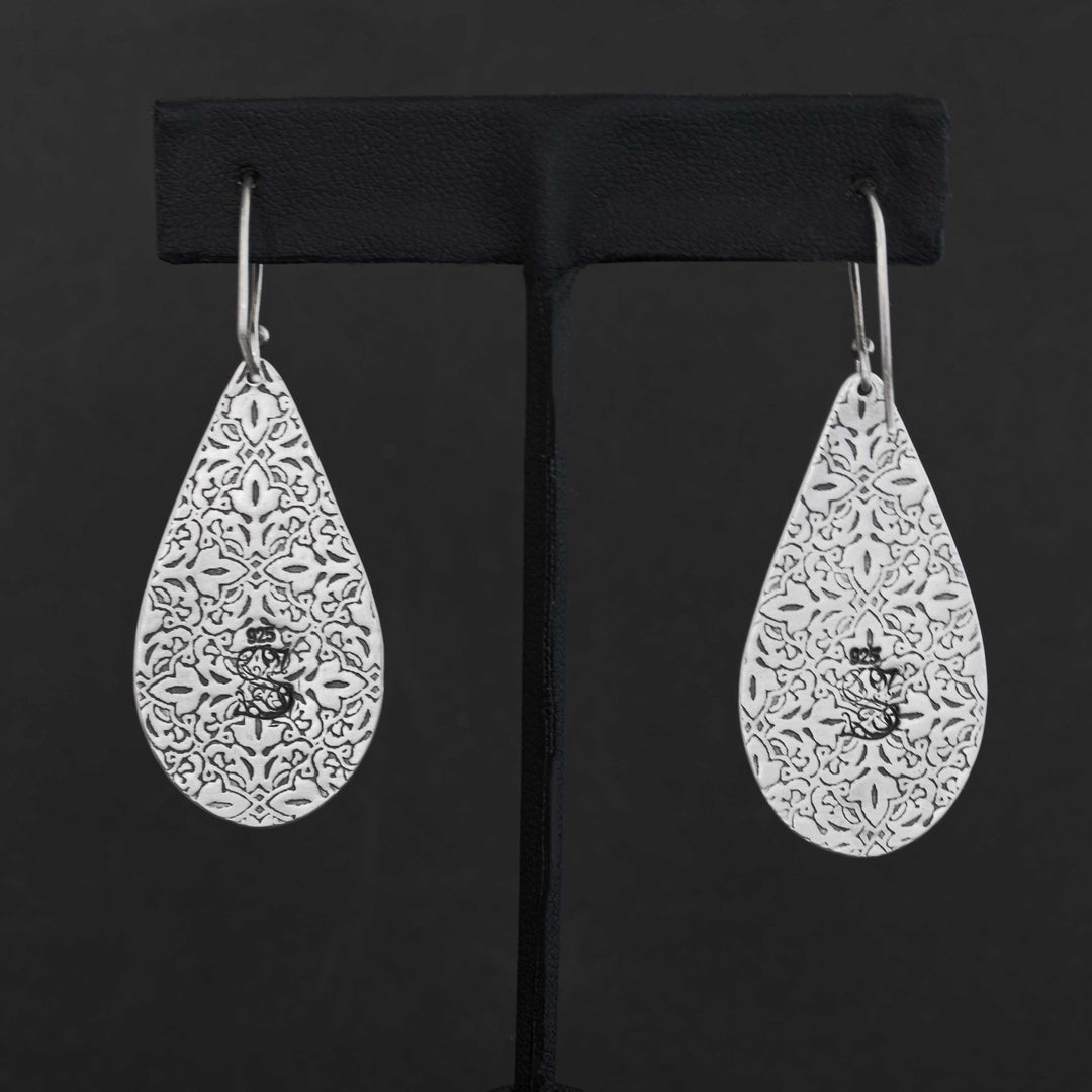Back of handmade sterling silver Blackjack turquoise earrings showing intricate pressed pattern detail and maker's mark