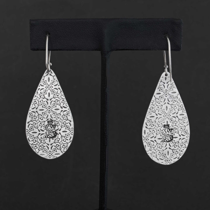 Back of handmade sterling silver Blackjack turquoise earrings showing intricate pressed pattern detail and maker's mark