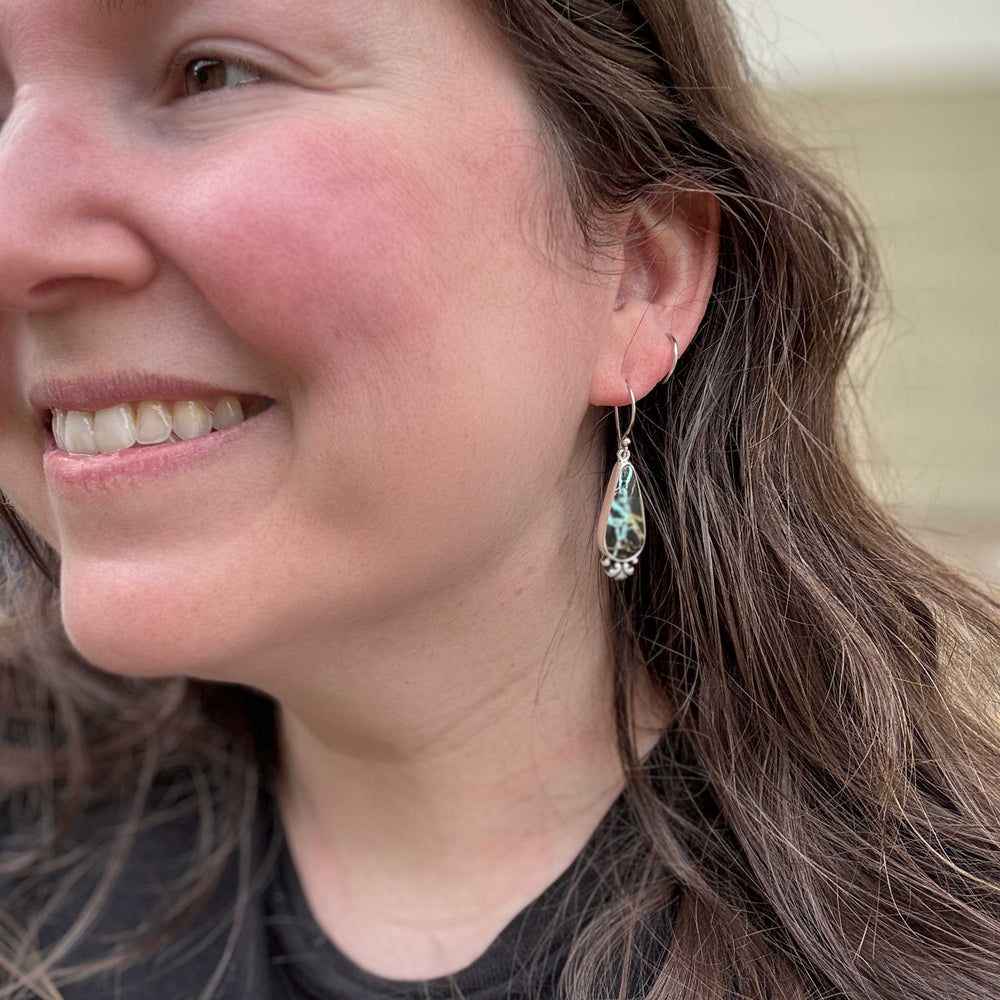 Blackjack turquoise teardrop earrings worn on model with dark hair and black top, handmade sterling silver dangle earrings, Colorado silversmith