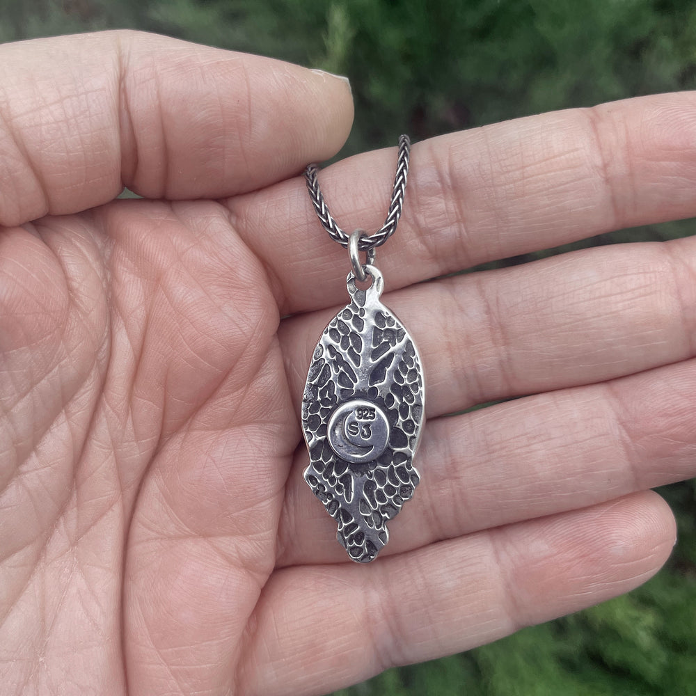 Back of handmade turquoise pendant with textured leaf pattern and oxidized details in sterling silver. Artisan jewelry crafted in Fort Collins, Colorado.