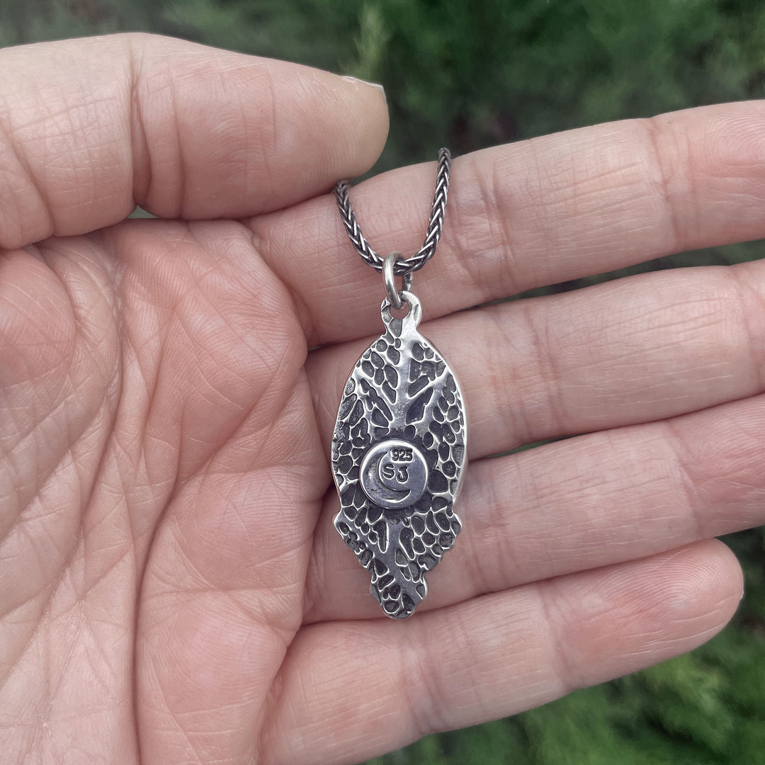 Back of handmade turquoise pendant with textured leaf pattern and oxidized details in sterling silver. Artisan jewelry crafted in Fort Collins, Colorado.