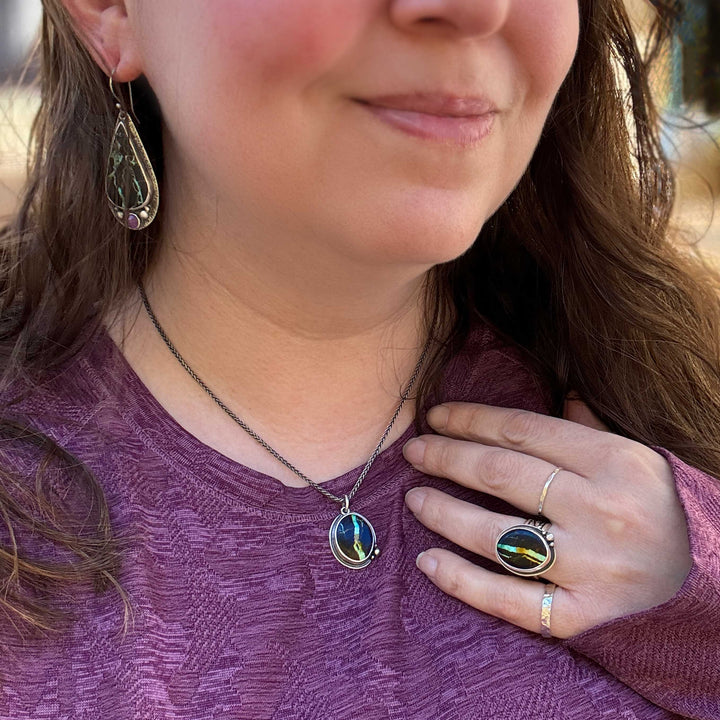Blackjack turquoise necklace and ring set styled on person wearing casual mauve top, with matching turquoise teardrop earrings, artisan silver jewelry