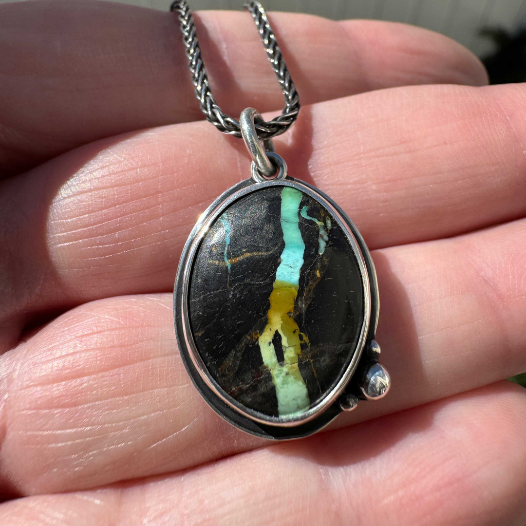 Nevada Blackjack turquoise oval pendant on wheat chain held in palm outdoors, one of a kind artisan necklace in sterling silver