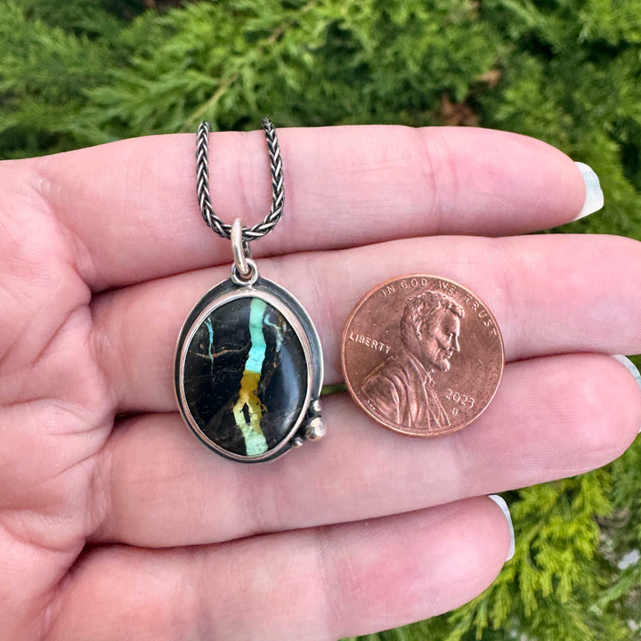 Blackjack turquoise pendant necklace size comparison with penny, showing scale of oval cab and sterling silver bezel setting, handmade in Colorado
