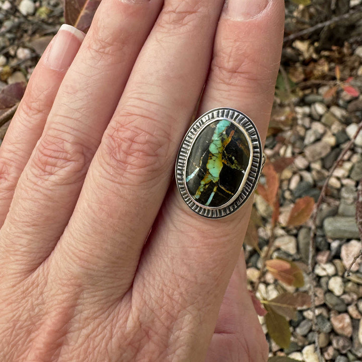 Blackjack turquoise statement ring worn on hand, showcasing bright turquoise veins against a dark matrix.