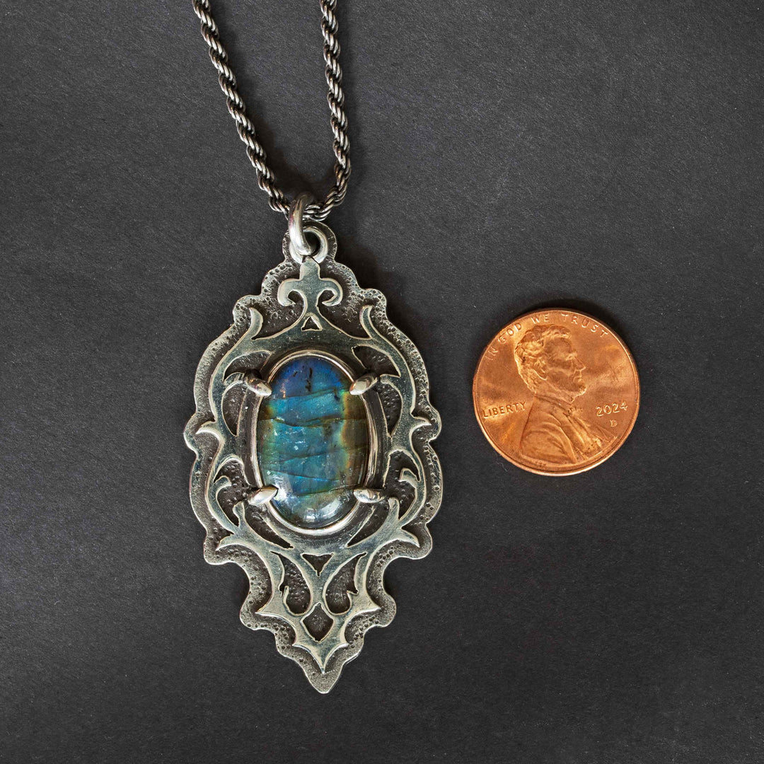 Blue labradorite gothic pendant with penny for size reference on black background