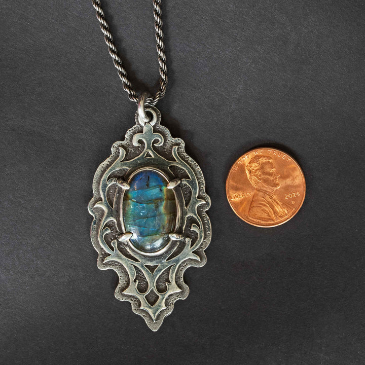 Blue labradorite gothic pendant with penny for size reference on black background