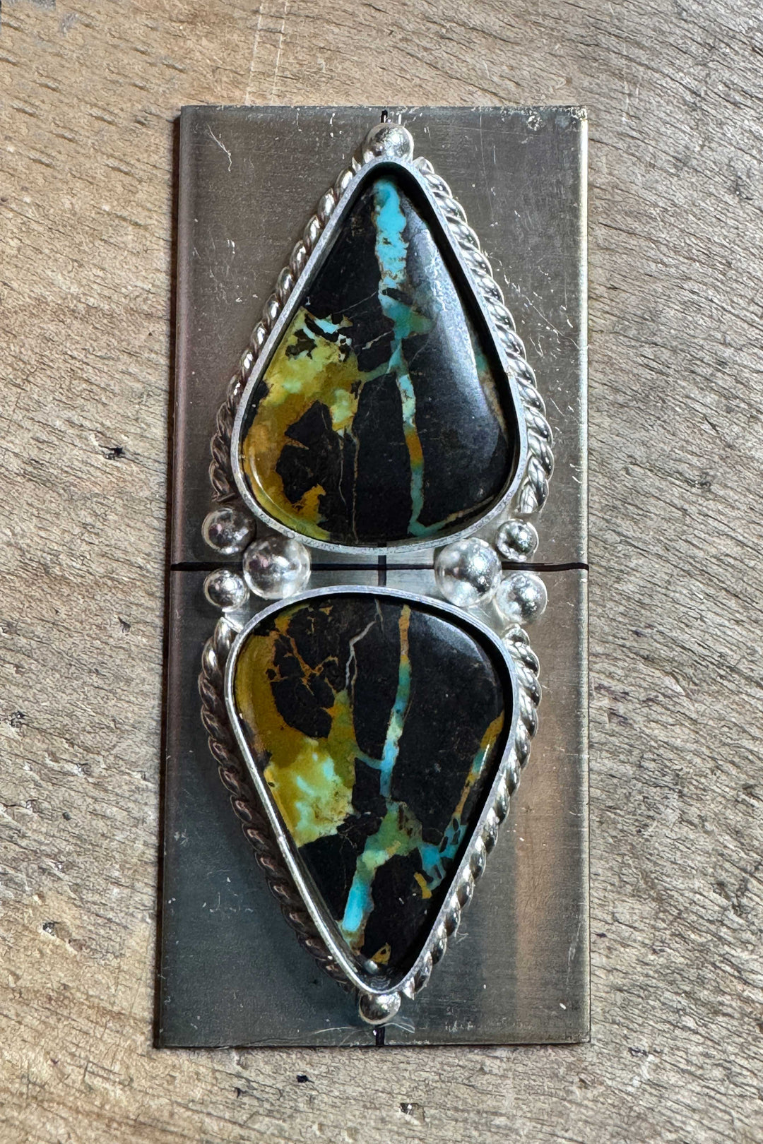 A custom silver ring in progress featuring two tear-drop shaped Blackjack turquoise stones. 