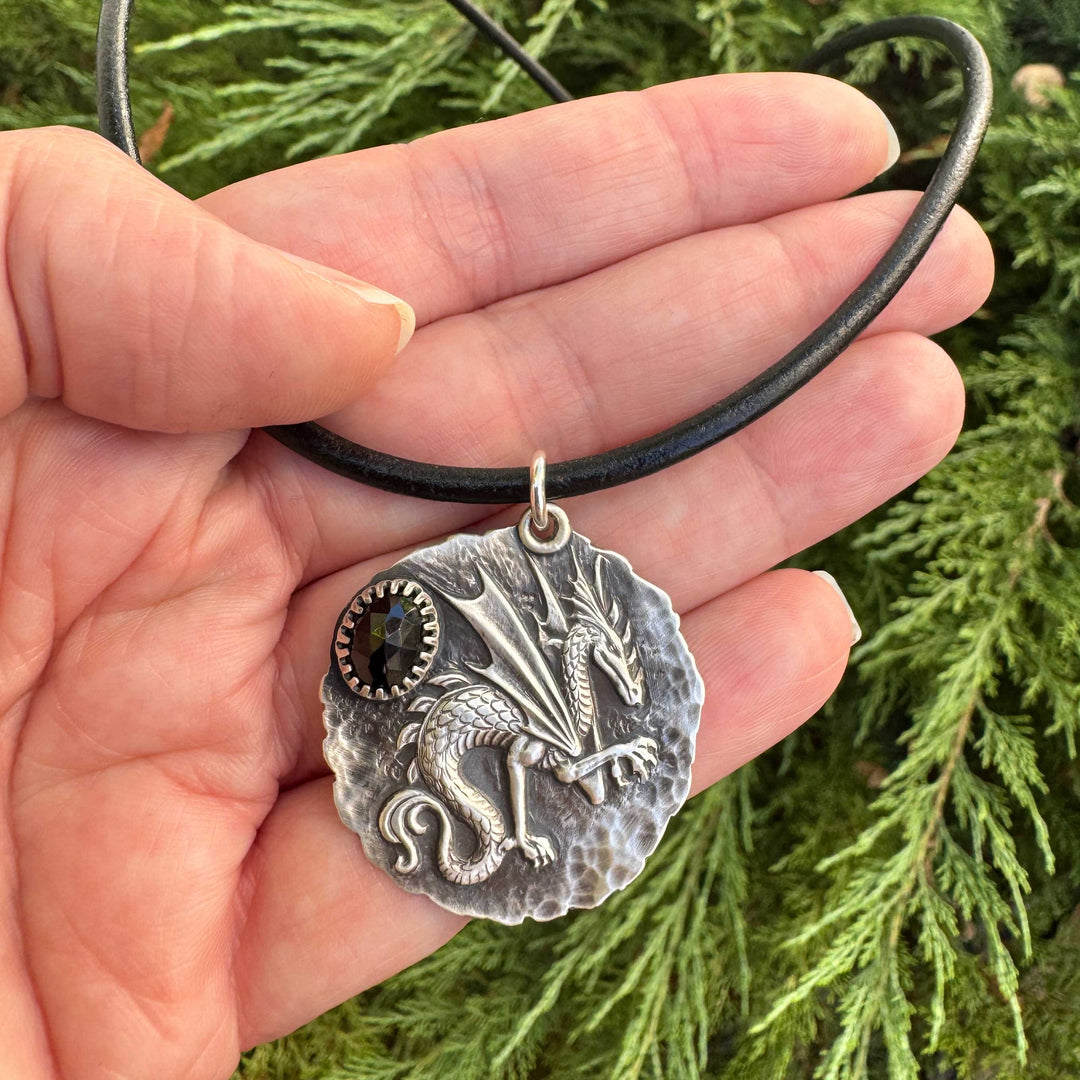 Sterling silver dragon necklace with black spinel shown in hand for scale