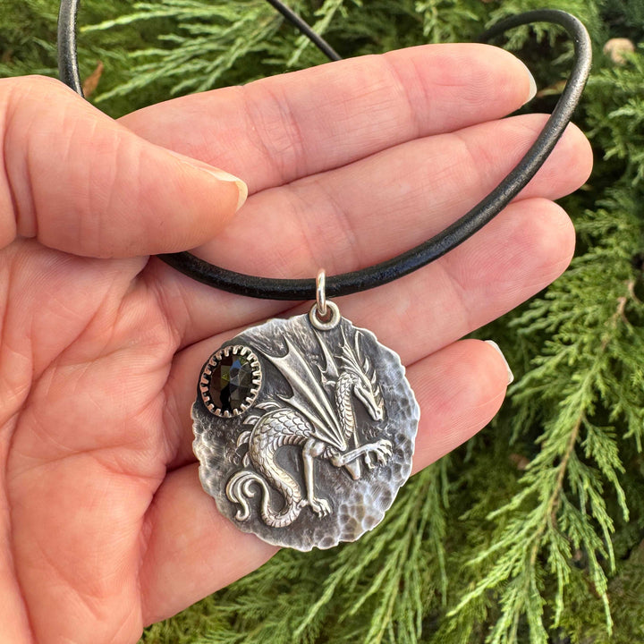 Sterling silver dragon necklace with black spinel shown in hand for scale