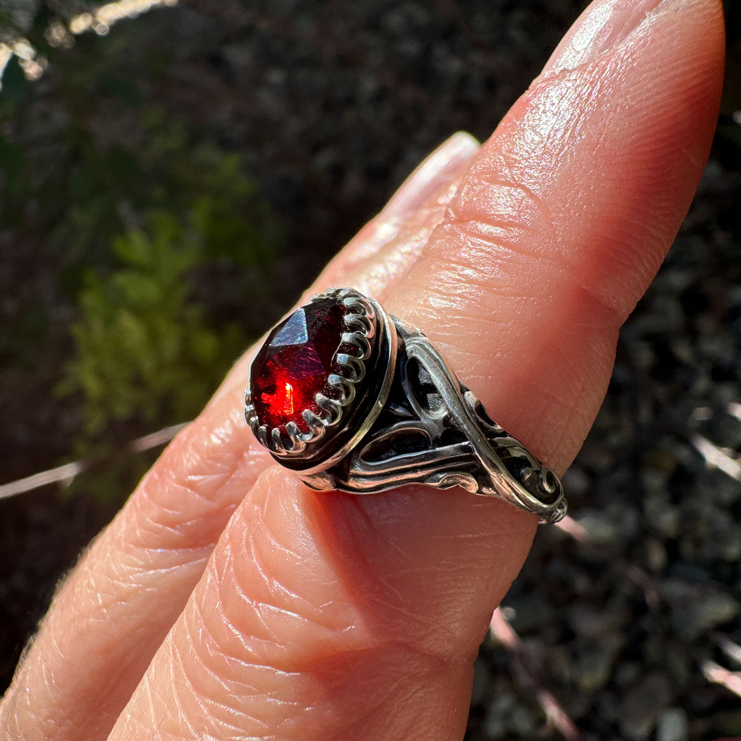 Sterling silver fantasy garnet ring with elven-style scrollwork band and crown bezel.