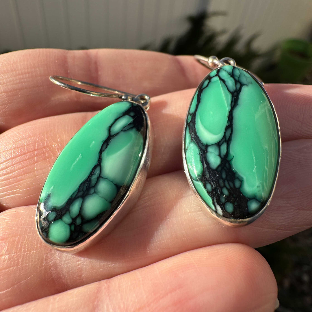 Detail view of oval Emerald Rose variscite stones in sterling silver dangle earrings.