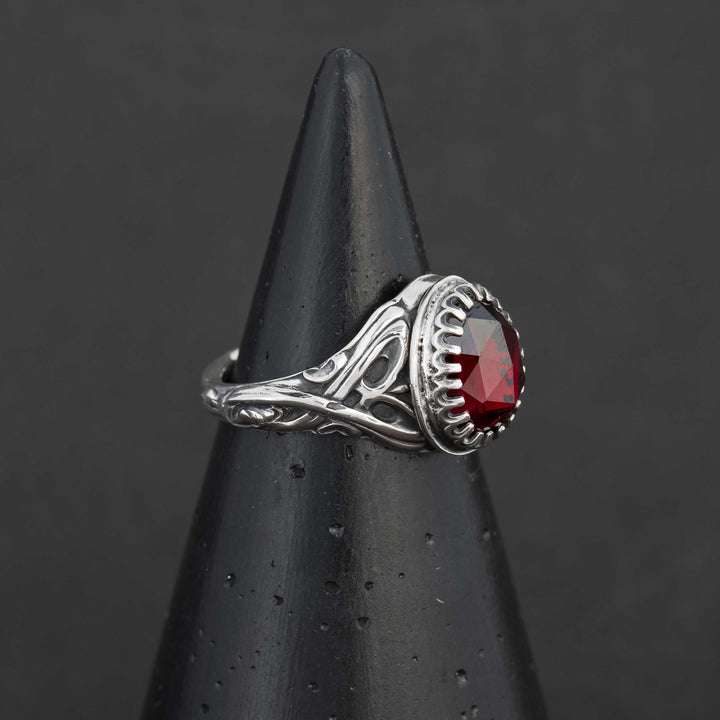 Profile view of the handcrafted sterling silver garnet ring, highlighting the intricate fantasy scrollwork band and rosecut gemstone.