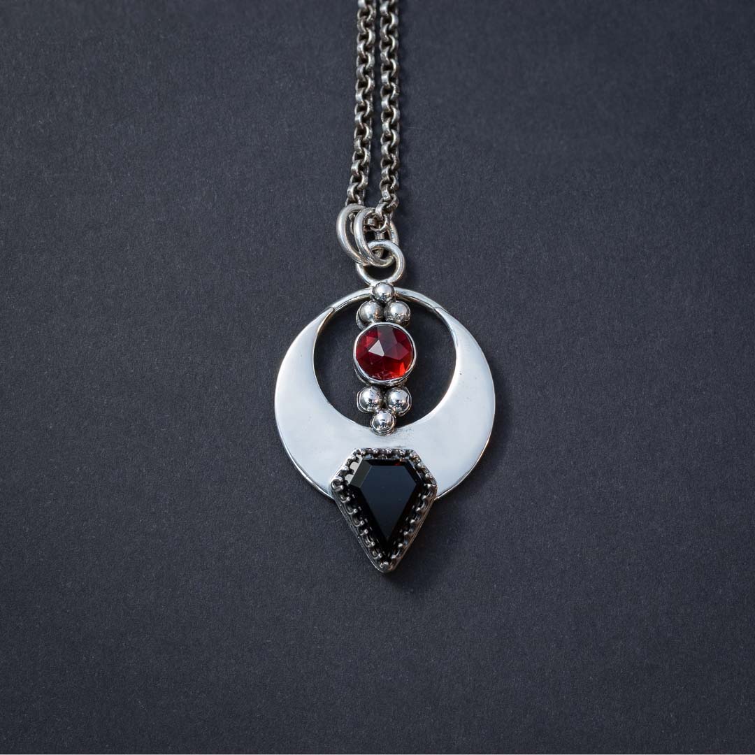 Handcrafted gothic jewelry featuring garnet and onyx in a vampire bat-inspired design.