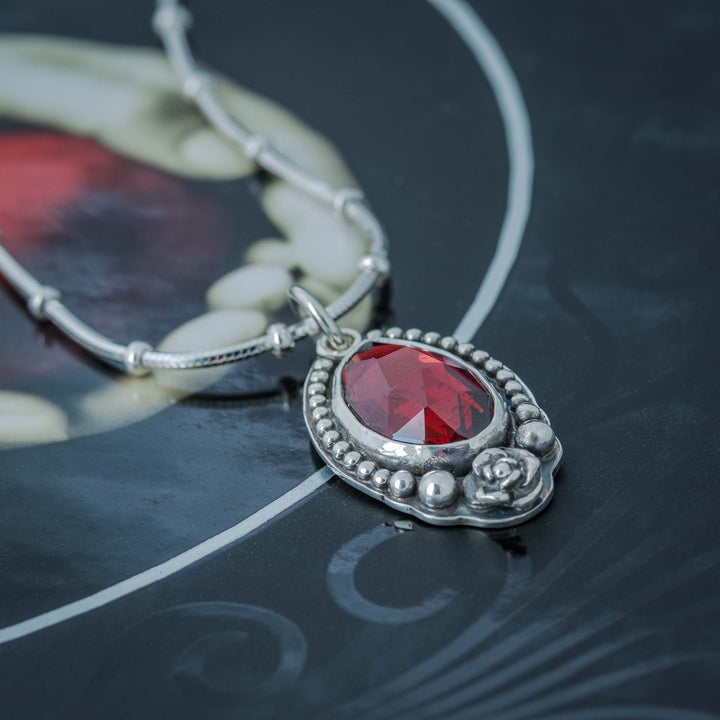 Red garnet rose pendant on a silver chain, perfect for gothic jewelry lovers.