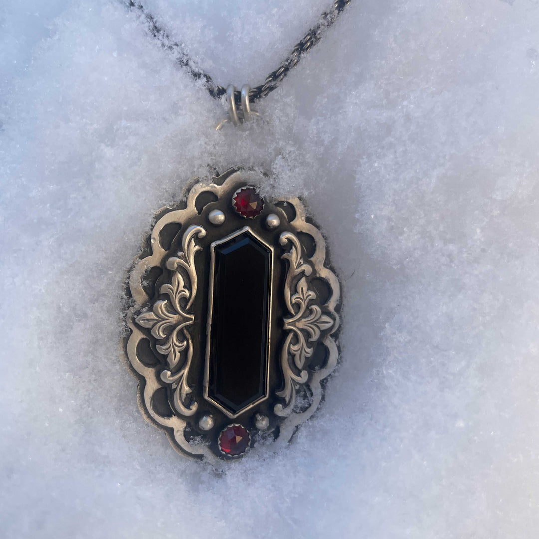 Gothic vampire statement necklace with black onyx and garnet resting in snow, featuring layered sterling silver and antique-style gothic detailing