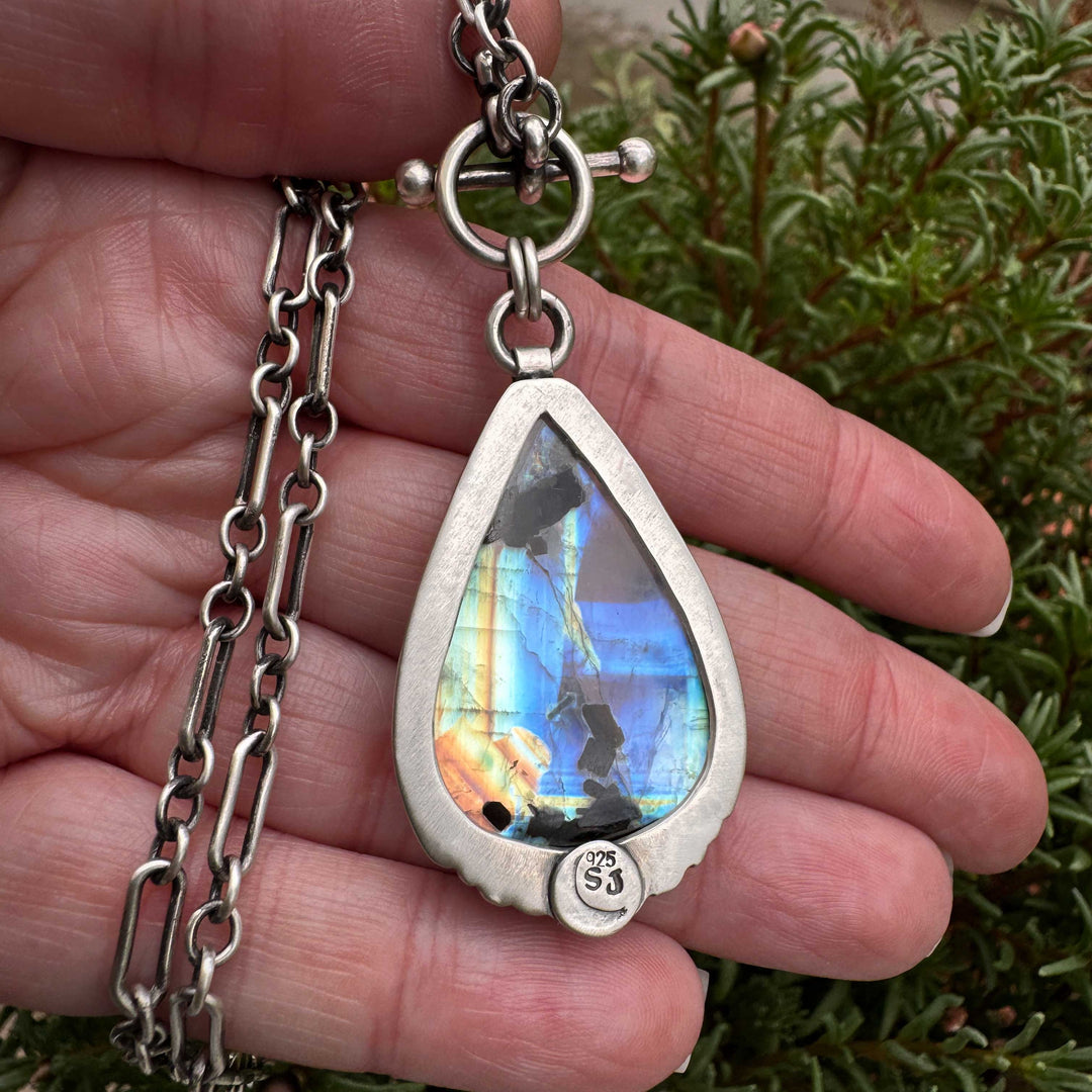 Handcrafted silver moonstone pendant in hand for scale showing artisan metalwork and gemstone size