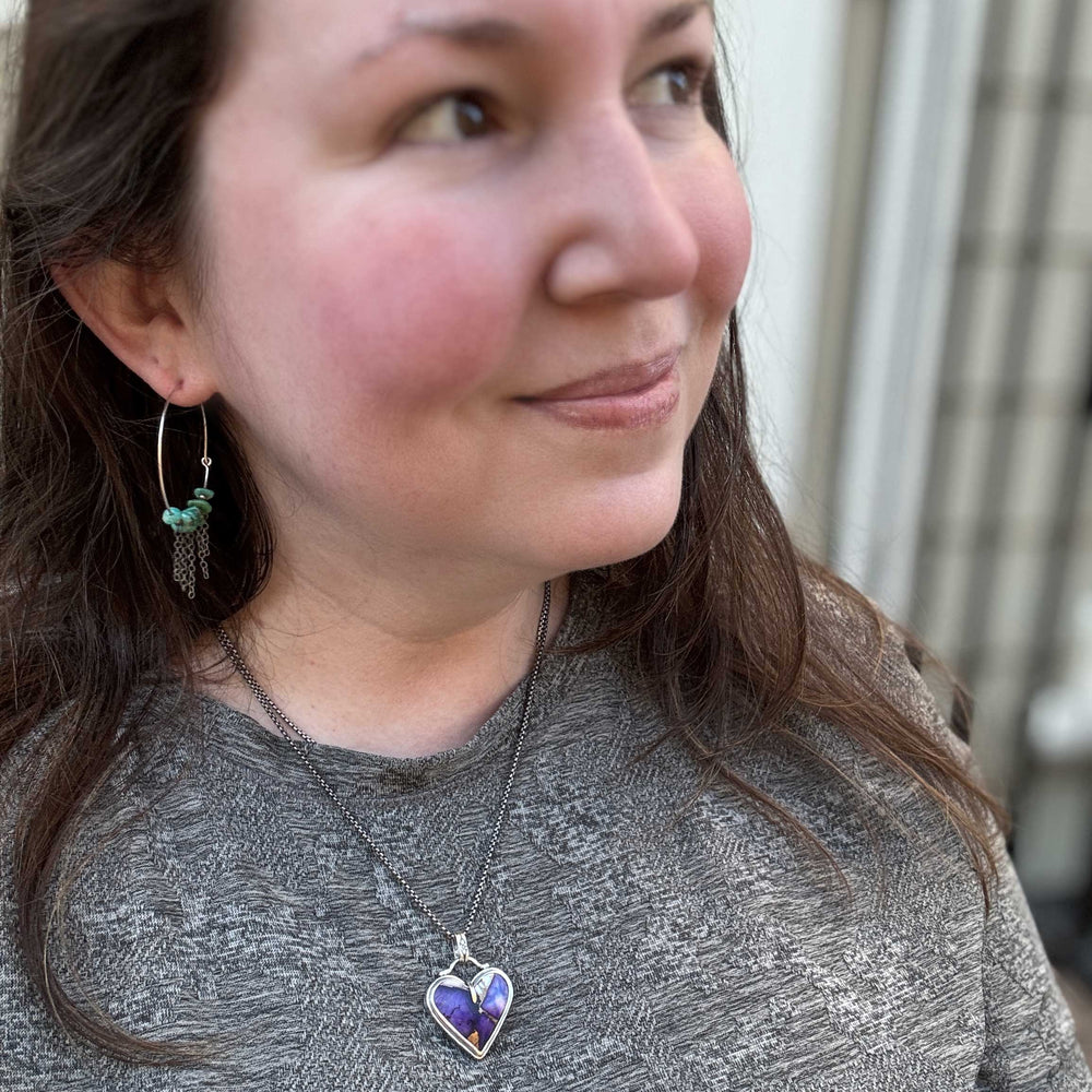 Woman wearing a necklace with a heart-shaped pendant, looking to the side.