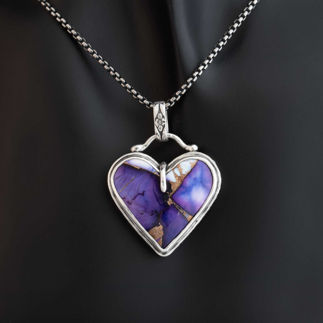 Heart-shaped pendant with purple stone and silver frame on a dark background