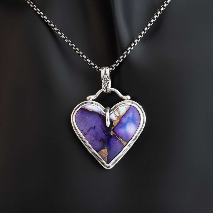 Heart-shaped pendant with purple stone and silver frame on a dark background