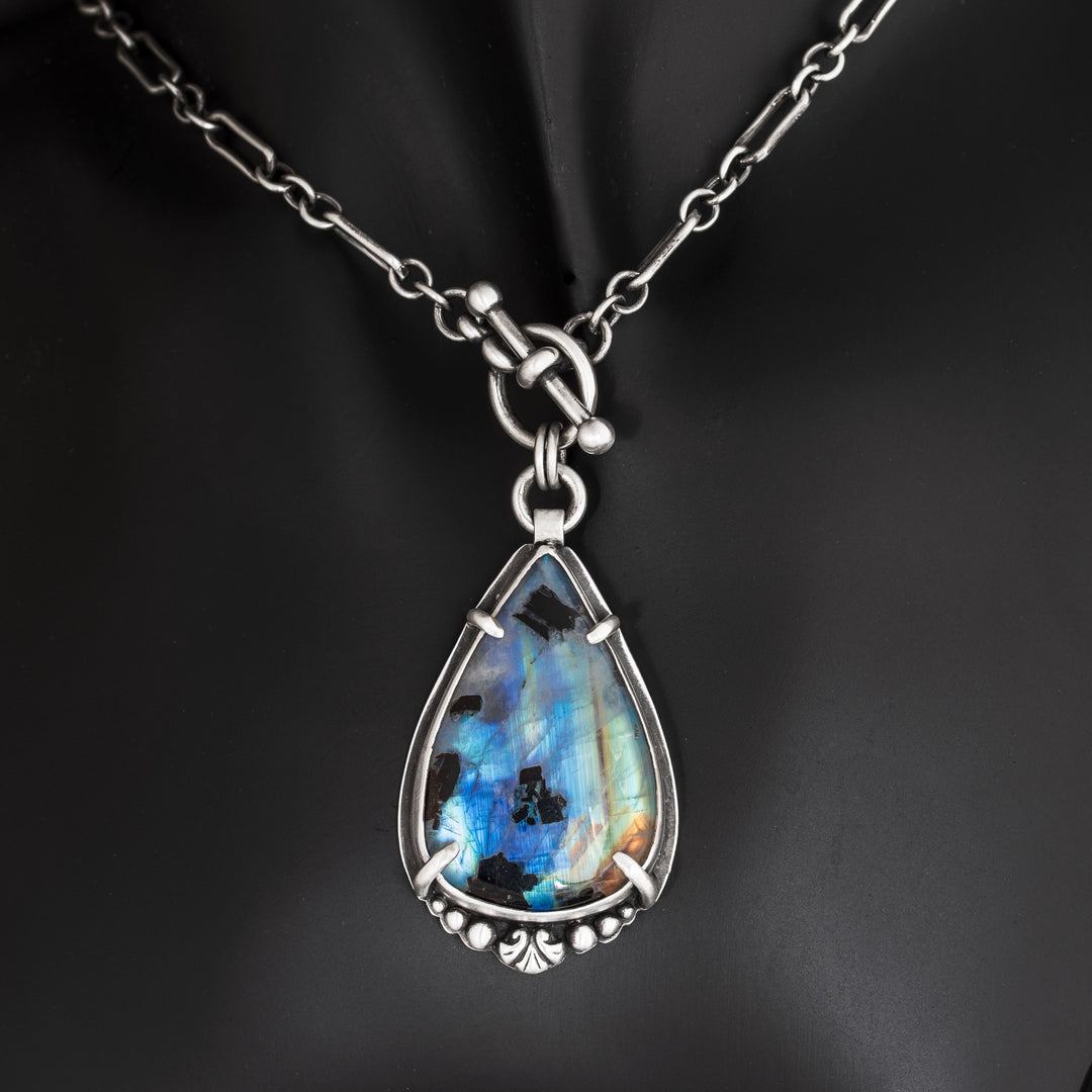 Close-up of rainbow moonstone pendant with black tourmaline showing blue flash and sterling silver details