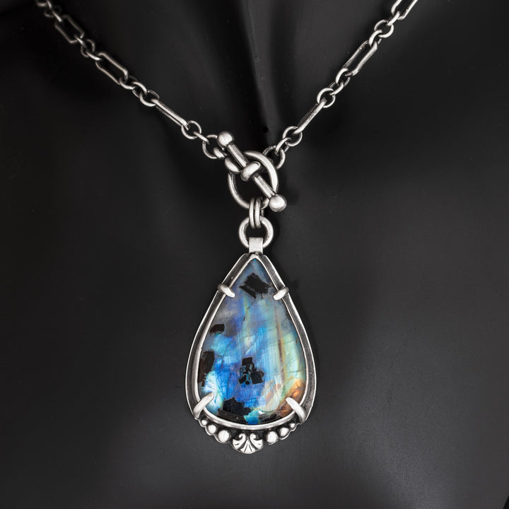 Close-up of rainbow moonstone pendant with black tourmaline showing blue flash and sterling silver details