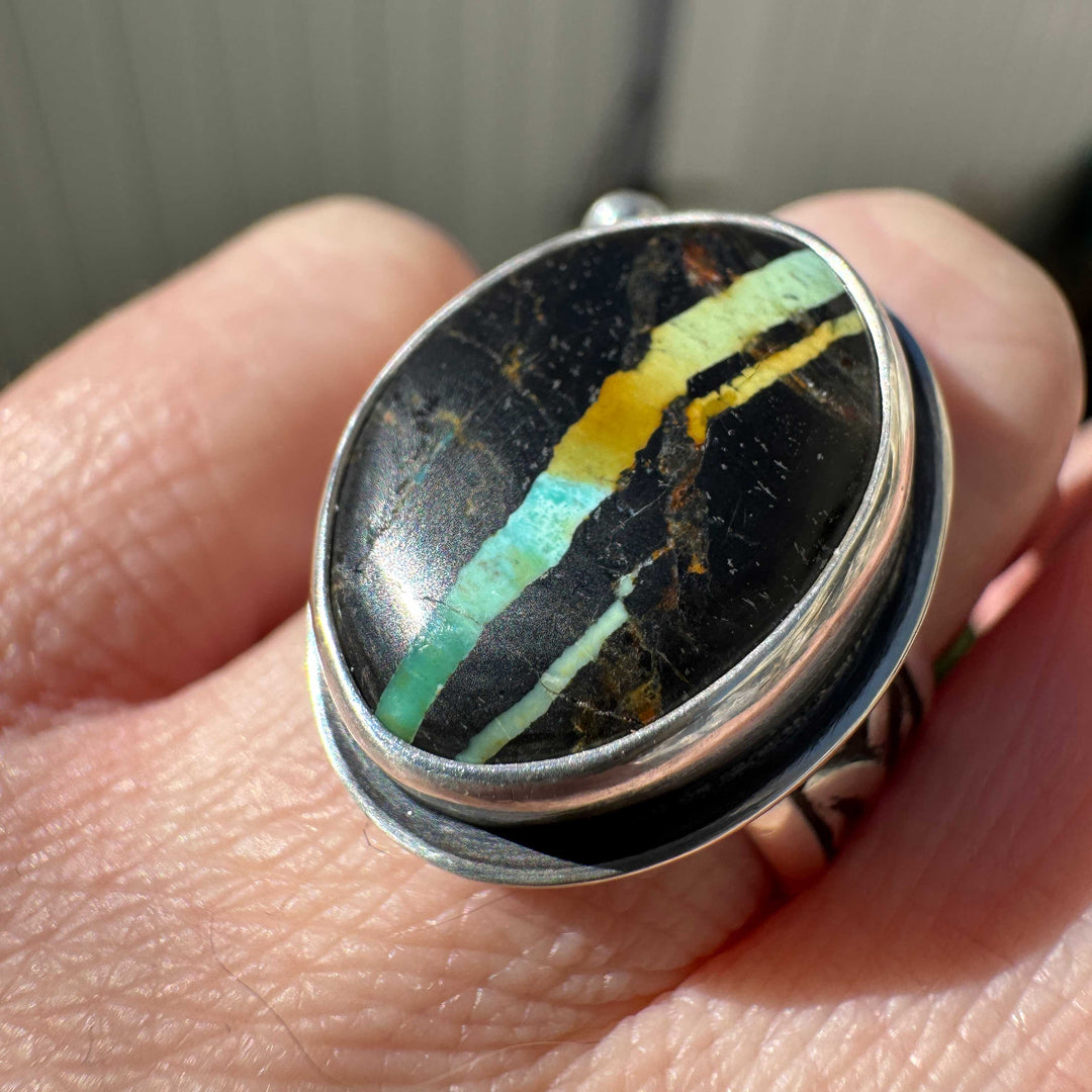 Rare Blackjack turquoise ring worn on hand outdoors, teal and gold ribbon matrix, artisan silver jewelry