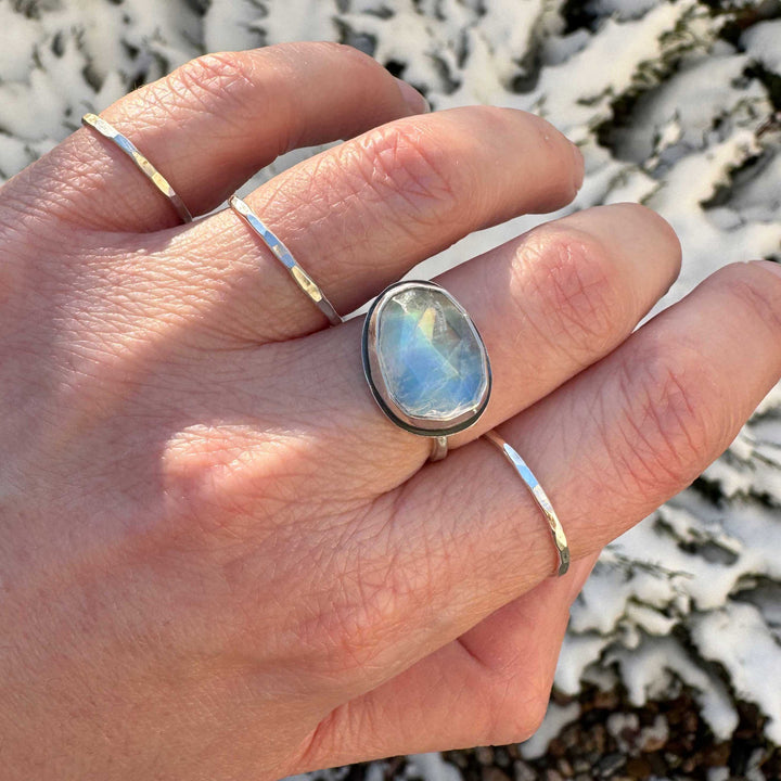 Rose cut rainbow moonstone ring size 7.5 worn alone on hand, snowy evergreen background