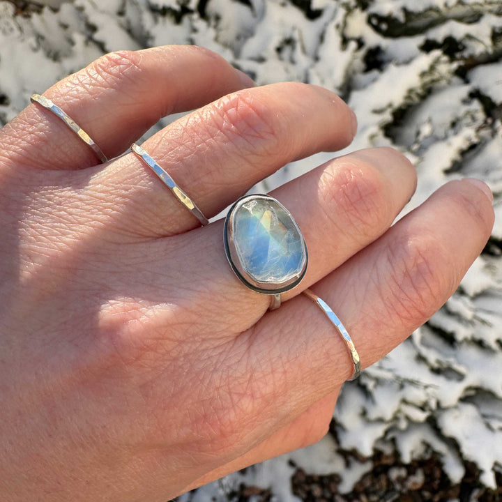 Rose cut rainbow moonstone ring size 7.5 on hand, blue flash with gold-to-orange rainbow, snowy background