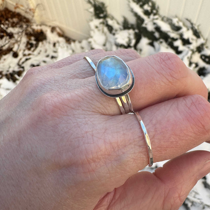 Close up of rose cut rainbow moonstone ring size 7.5 stacked with hammered sterling silver bands, strong blue flash