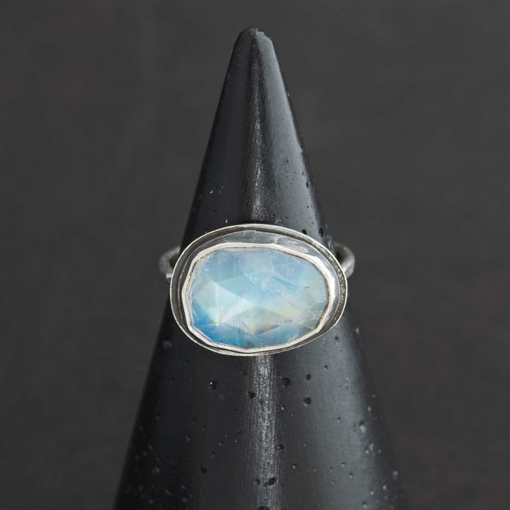 Handmade rose cut rainbow moonstone ring size 7.5 in sterling silver bezel, horizontal egg shape, front view on cone display
