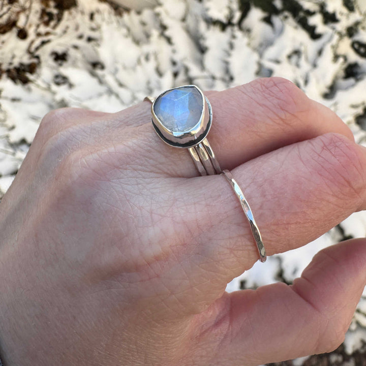 Rose cut rainbow moonstone bezel ring stacked with two hammered silver bands, close up detail