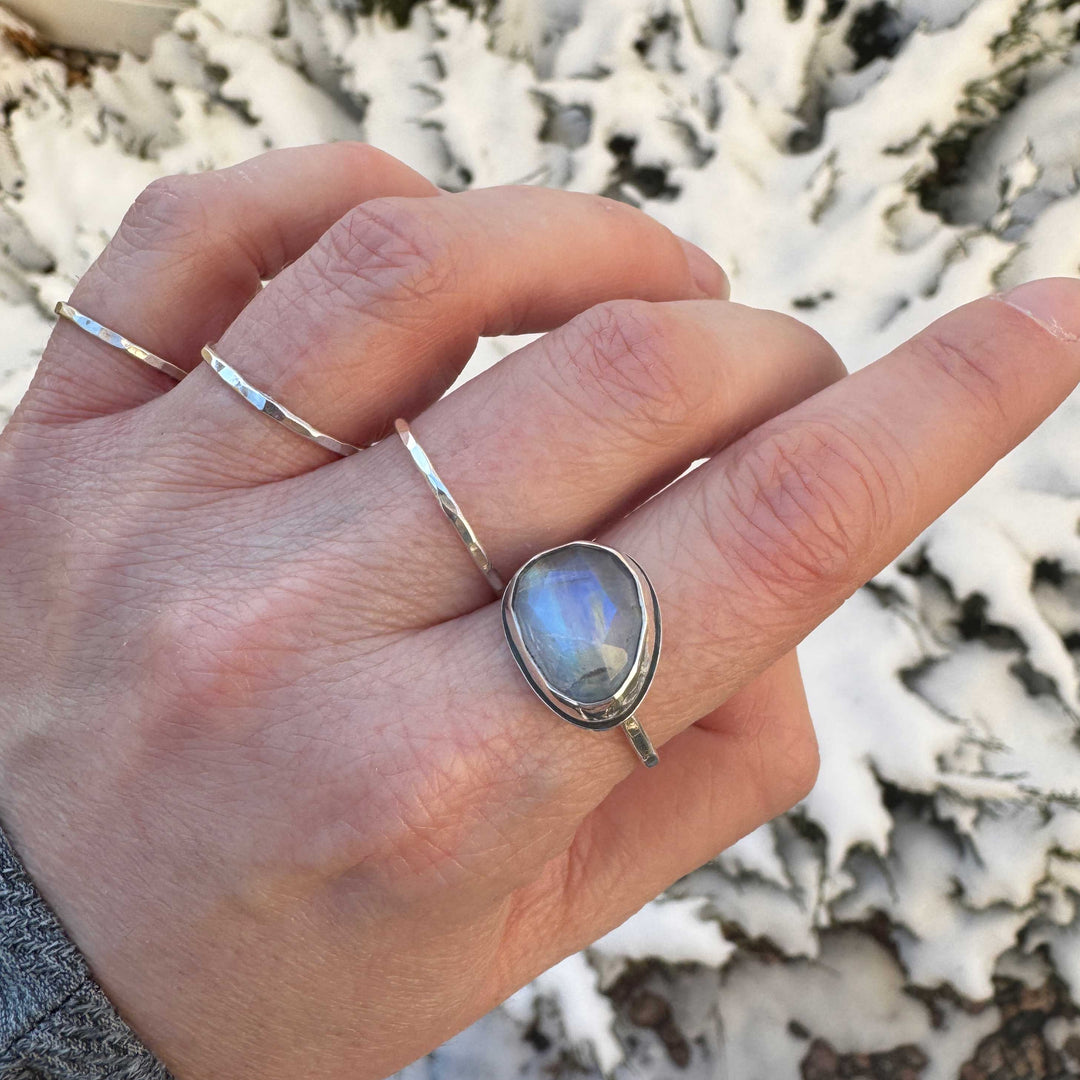 Rose cut rainbow moonstone ring size 9.5 worn on hand with hammered stacker bands, deep blue-purple flash, snowy background