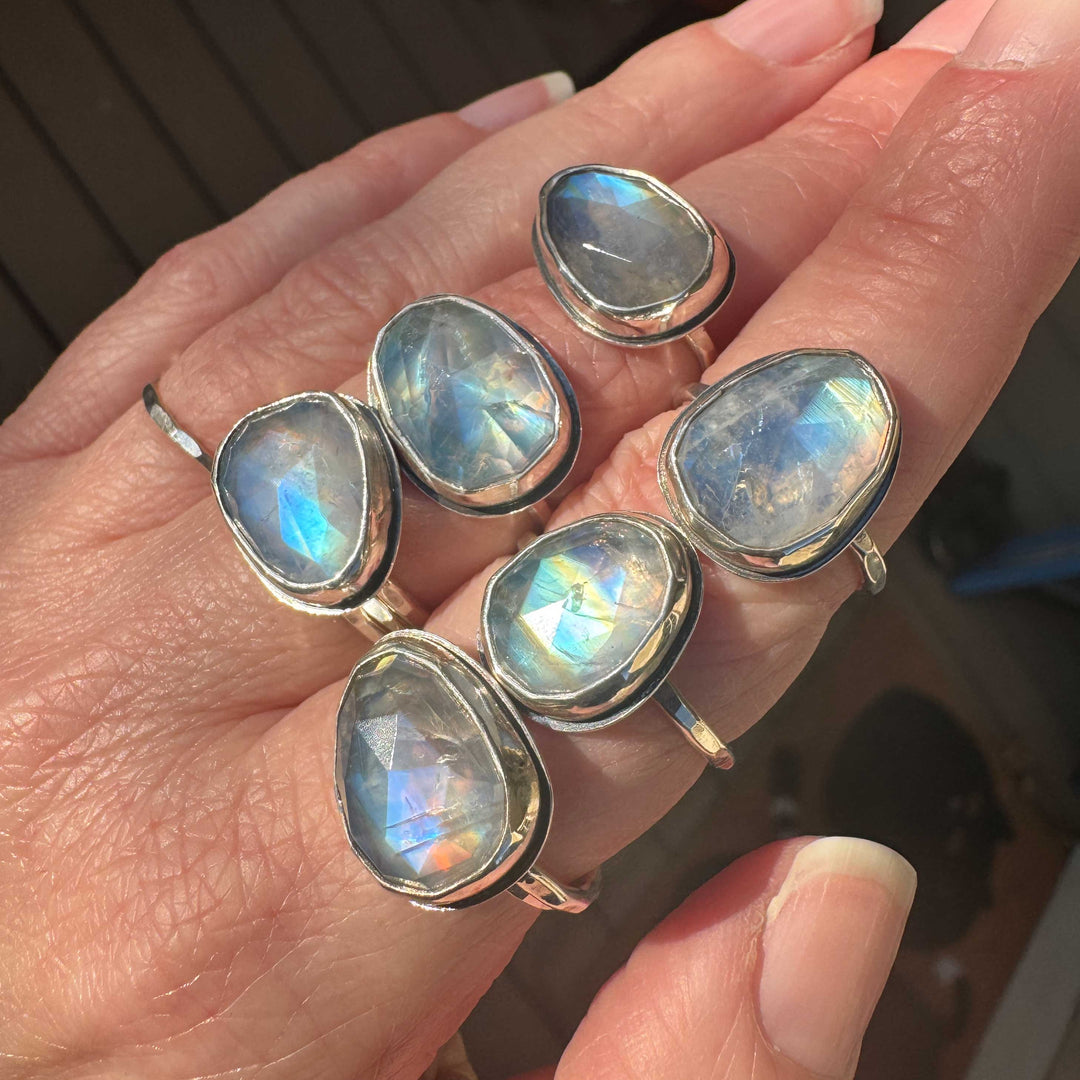 Collection of six handmade rose cut rainbow moonstone sterling silver rings stacked on fingers