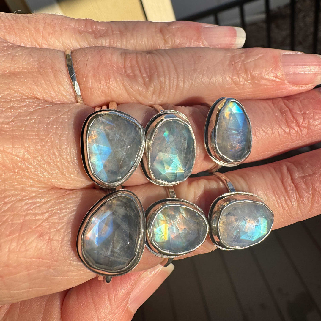 Multiple rose cut rainbow moonstone rings in sterling silver bezels, various sizes, natural light