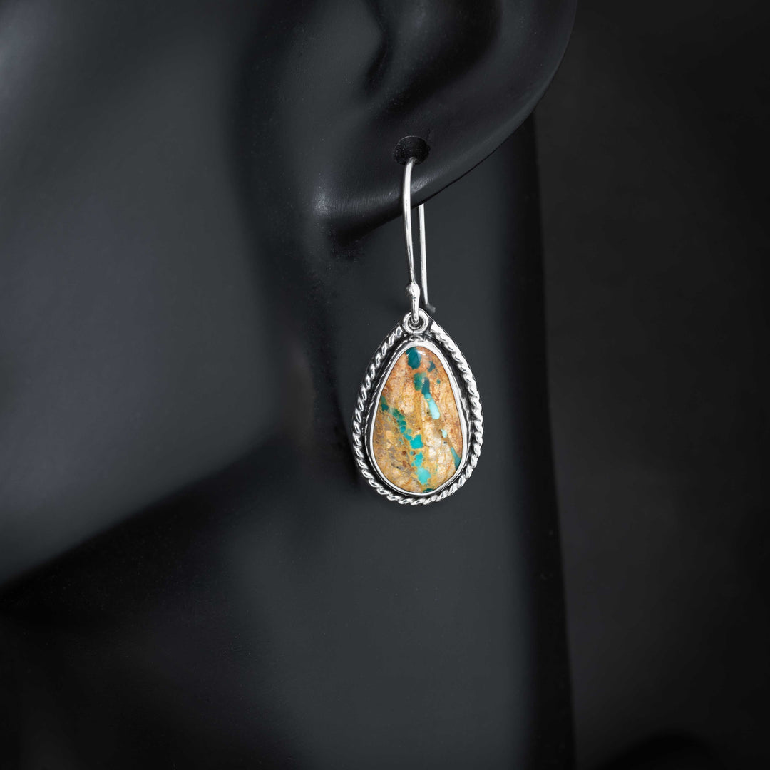 Royston Ribbon turquoise teardrop earring in sterling silver shown worn, with turquoise ribbon veining and twisted rope border.