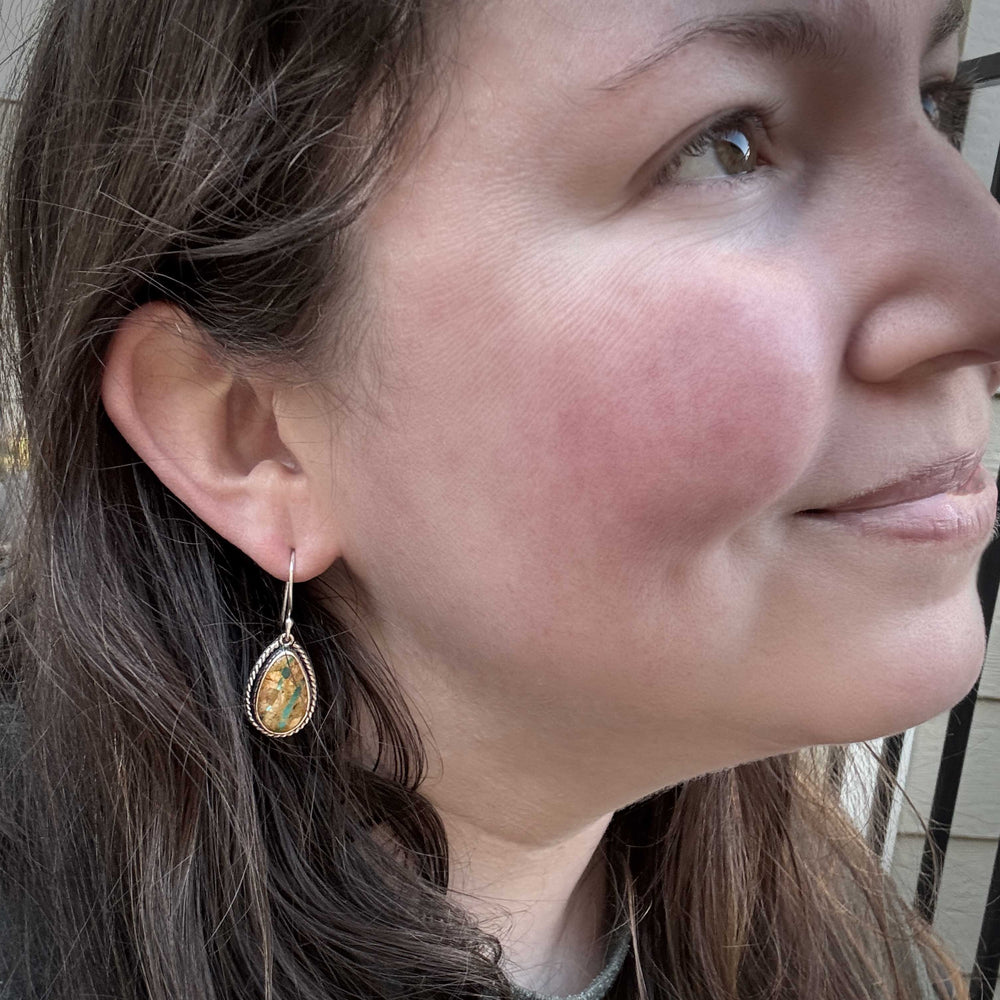 Model wearing Royston Ribbon turquoise earrings in sterling silver, highlighting teardrop shape and turquoise ribbon pattern.