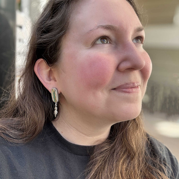 Lifestyle photo showing Royston Ribbon turquoise earrings worn, handmade in sterling silver.