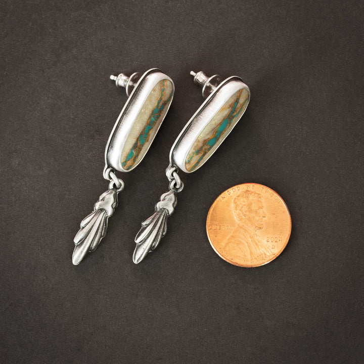 Royston Ribbon turquoise drop earrings beside a penny for scale, showing their artisan craftsmanship.
