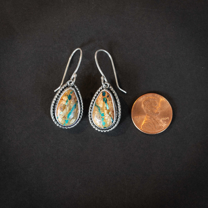 Royston Ribbon turquoise earrings beside a penny for scale, handmade sterling silver with earthy turquoise ribbon stones.