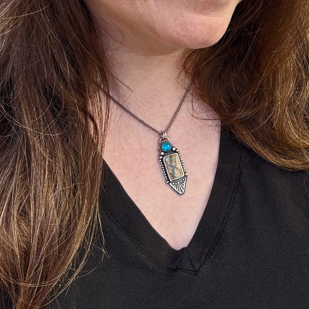 Unique Turquoise Necklace with a pendant worn by a person with long brown hair, against a black background.